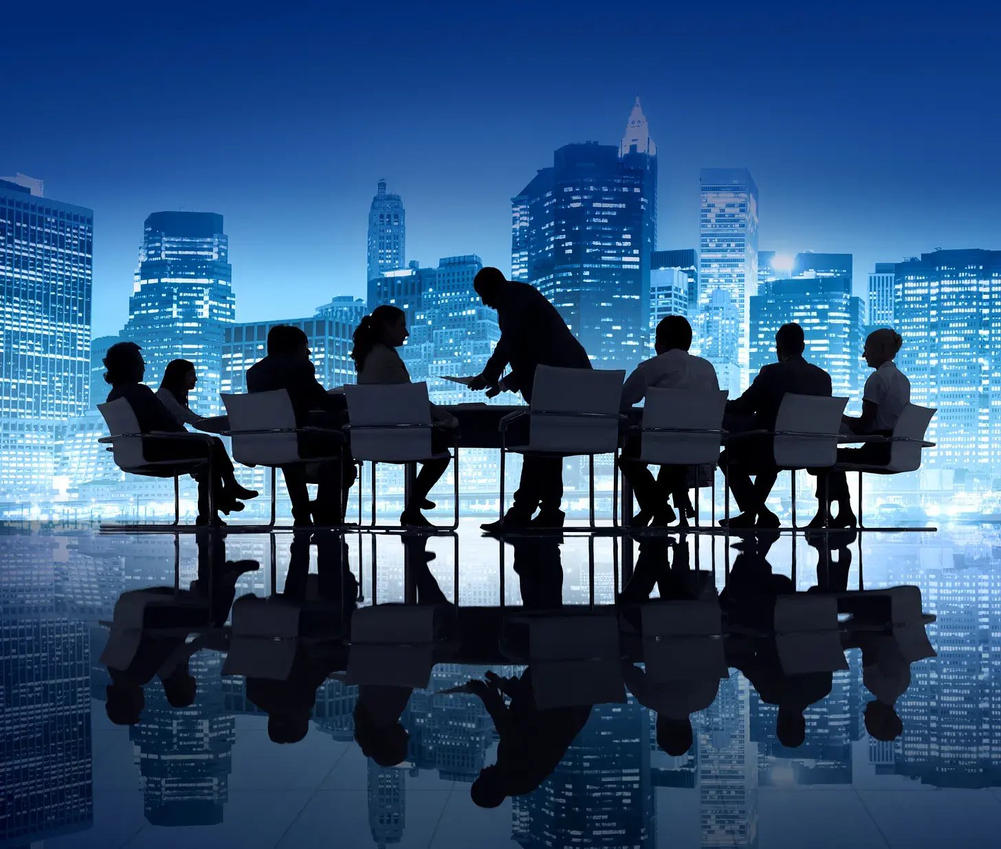 Silhouetted board members gathered around a conference table against a blue city skyline.